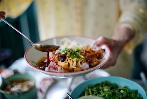 Fresh salad with mango slices, shrimp, and creamy dressing on wooden table