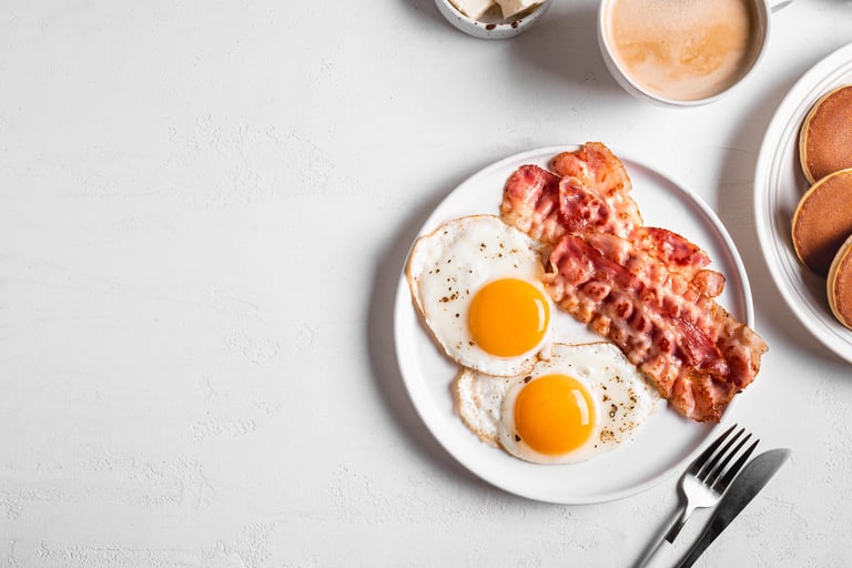 Breakfast with fried eggs, bacon, pancakes and coffee, top view, banner.