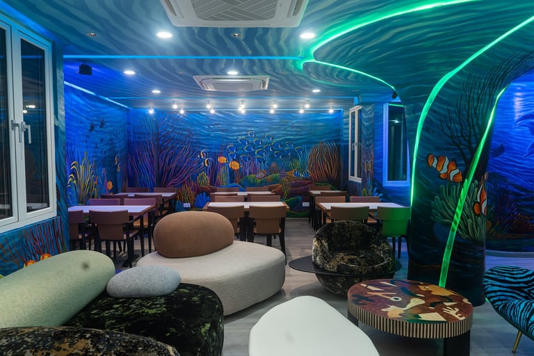 Modern underwater-themed lounge with neon blue and green lighting, coral murals, pod seating, and ambient tables