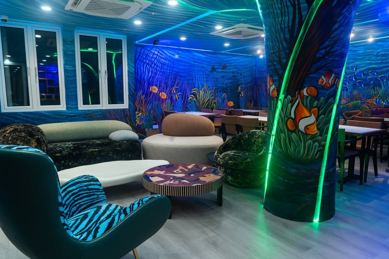 Modern lounge interior with blue ocean-themed murals, neon green accent lighting on columns, contemporary curved furniture, and underwater-inspired wall art