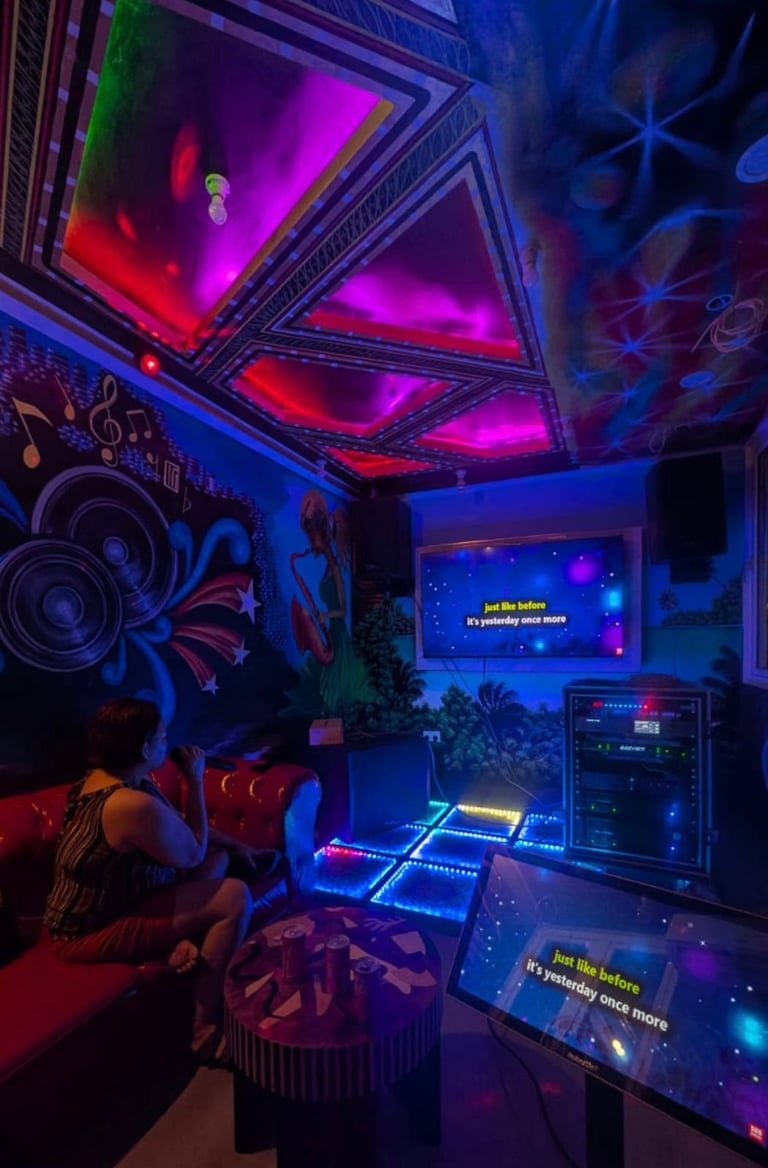 Vibrant neon nightclub interior with LED dance floor, colorful ceiling lights, DJ equipment, and music-themed wall art