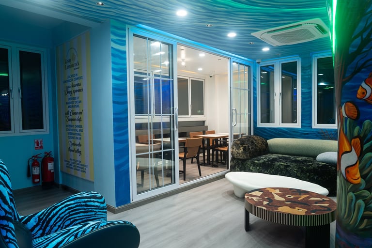 Modern blue-themed room with glass partitions, colorful wall murals, LED lighting, and contemporary furniture including zebra-striped seating